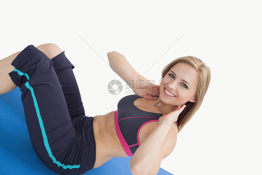 快乐的年轻女子在运动垫子上做静坐姿势的肖像仰卧起坐拉伸力量女性幸福运动垫运动服浅色头发身体图片