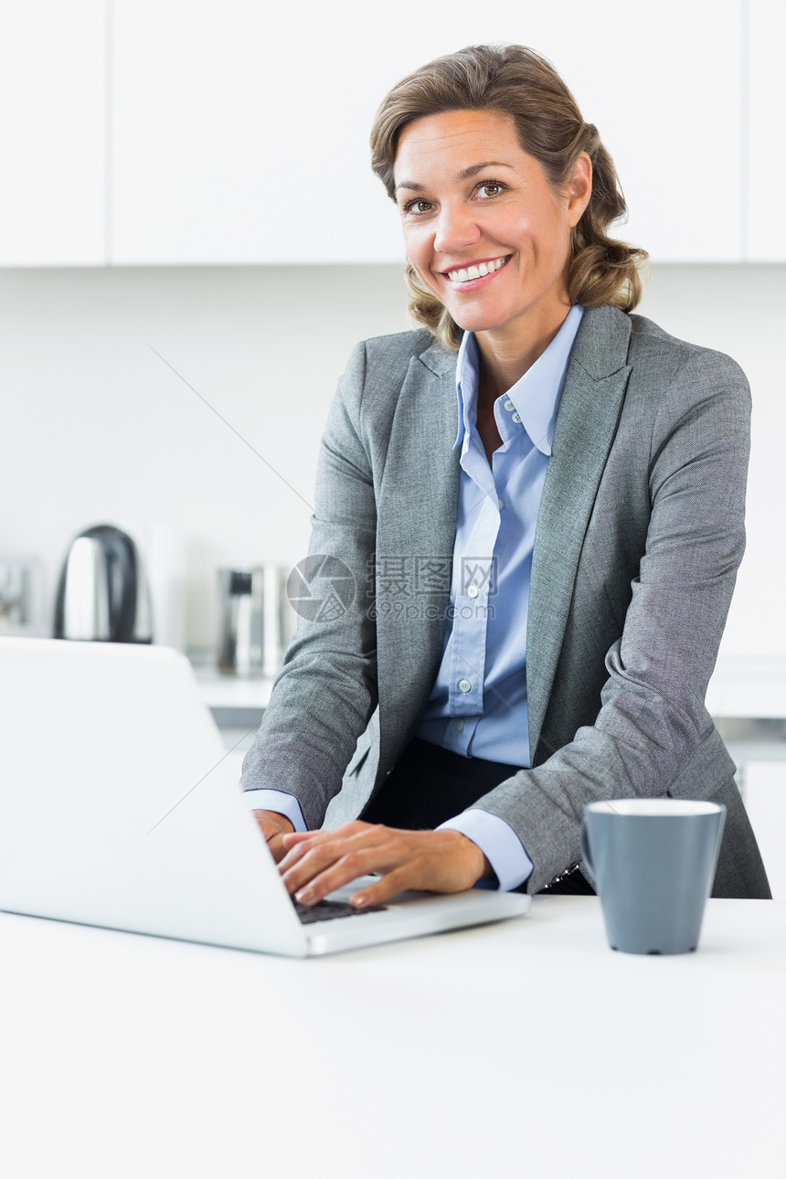 妇女上班前在厨房用笔记本电脑打字图片