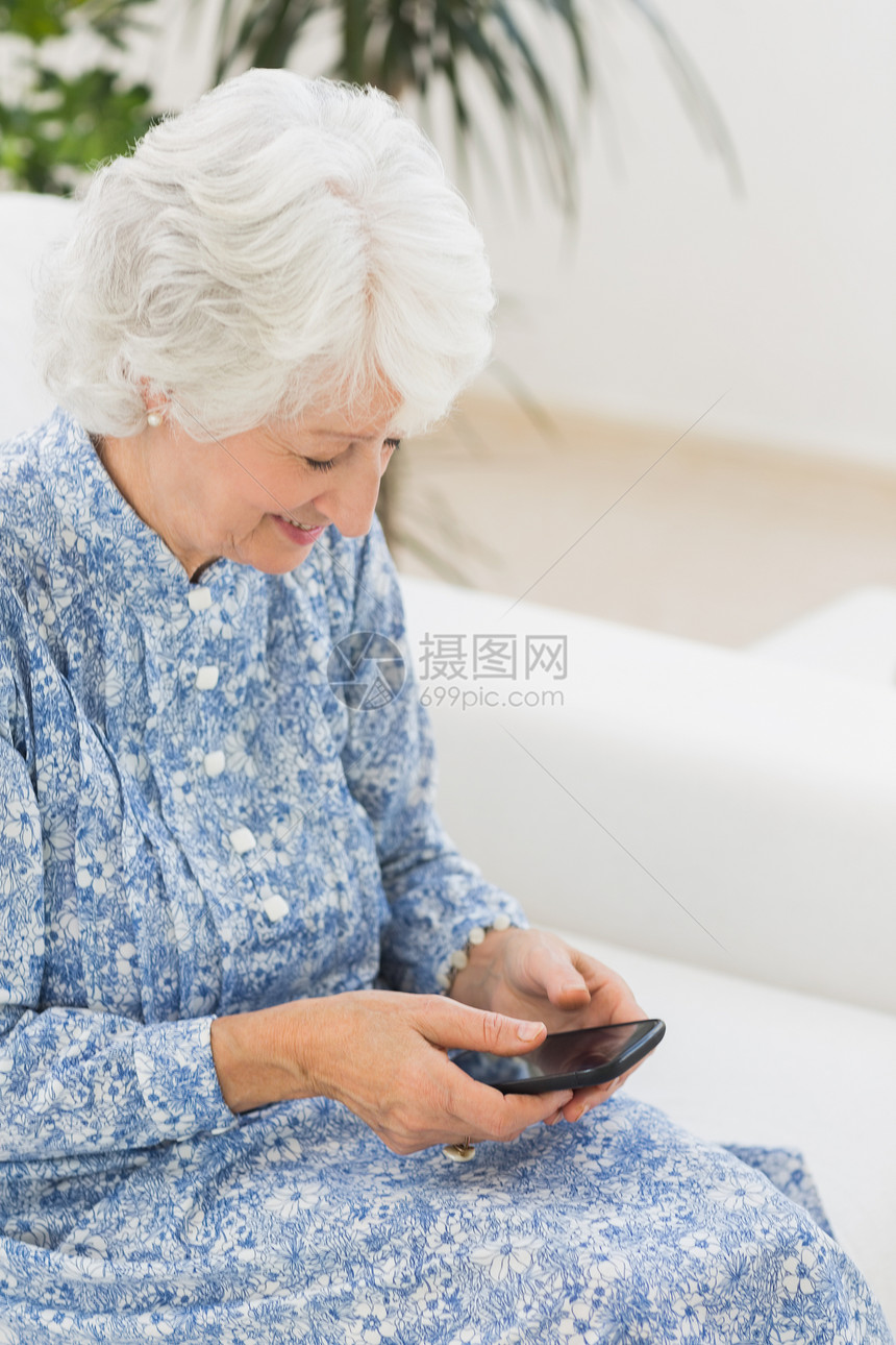使用智能手机的年长快乐妇女岁月电话房子女士女性流金沙发退休技术屏幕图片