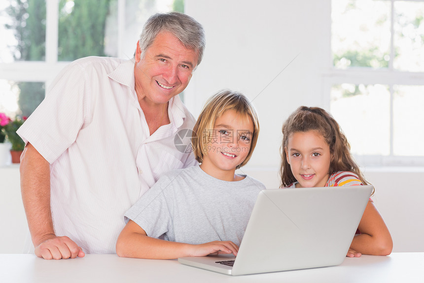 祖父和孩子们看着摄影机前方有笔记本电脑图片