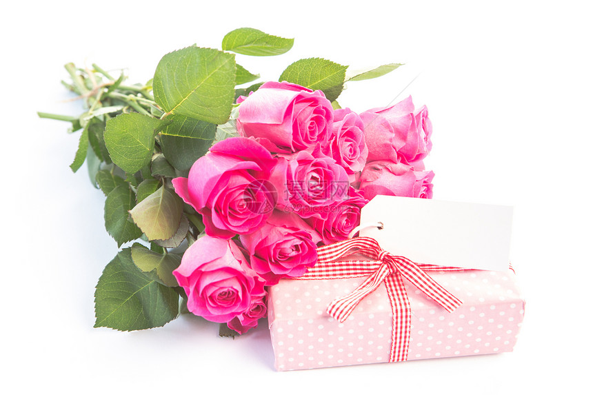 粉红色玫瑰的一束花 紧靠着一张带空白卡的礼物图片