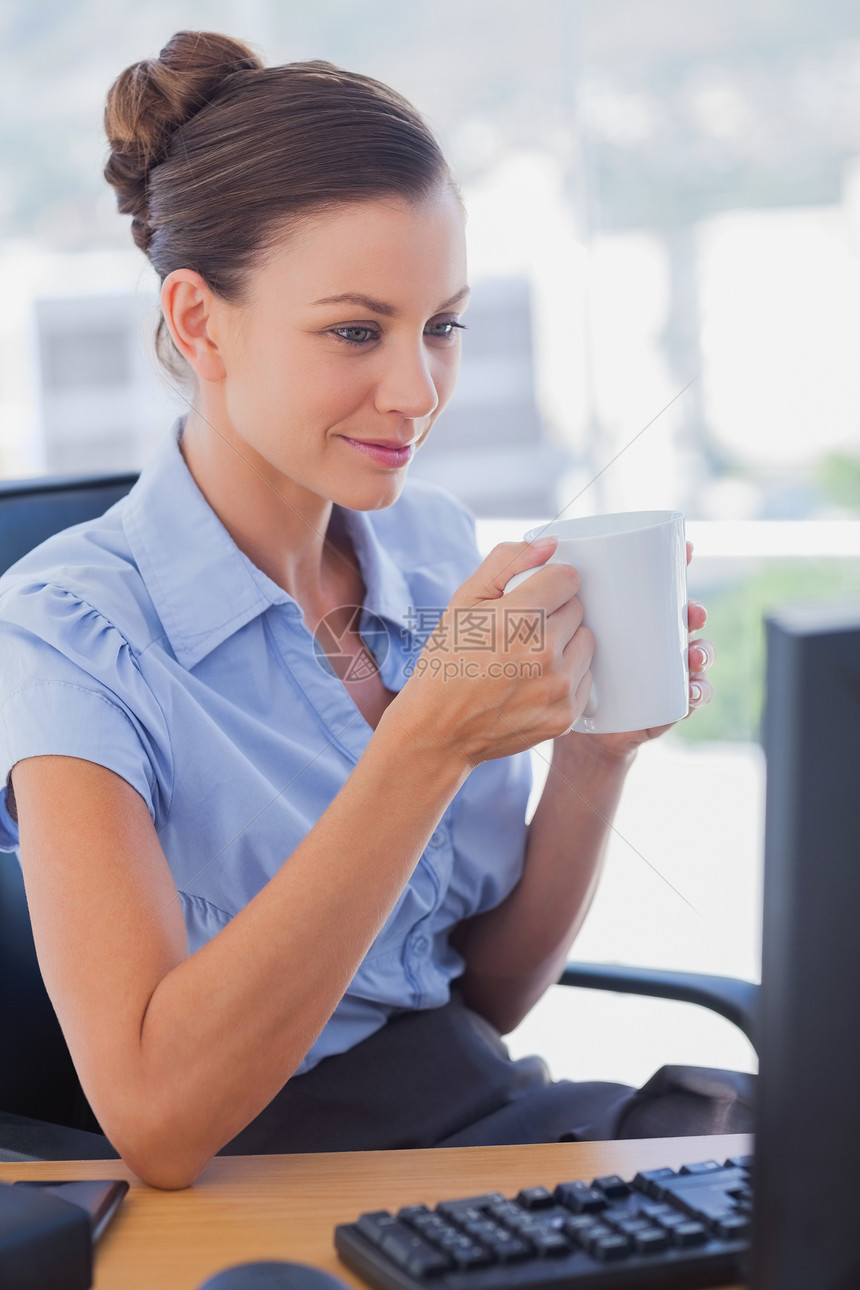 女商务人士拿着她的杯子微笑着笑键盘桌子快乐电脑电子棕色咖啡公司老鼠头发图片