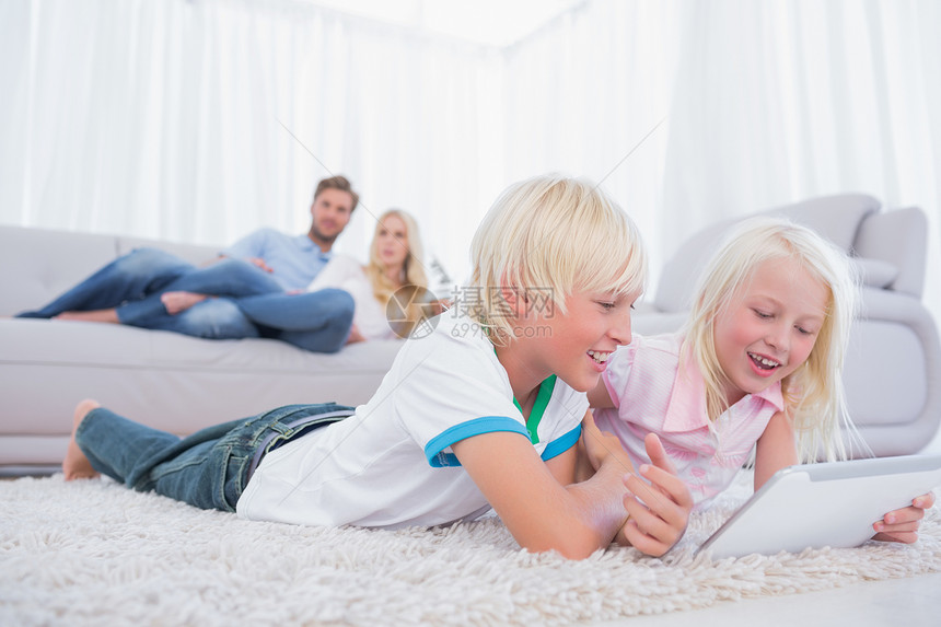 儿童用数字平板电脑躺在地毯上图片