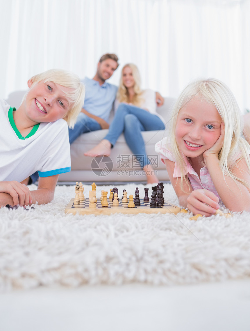 躺在地毯上玩象棋的儿童图片