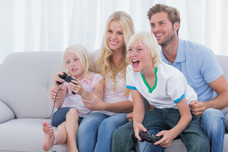 竟争玩电子游戏的家庭休息室男生长椅儿子金发女郎兄弟头发母亲短发长发背景