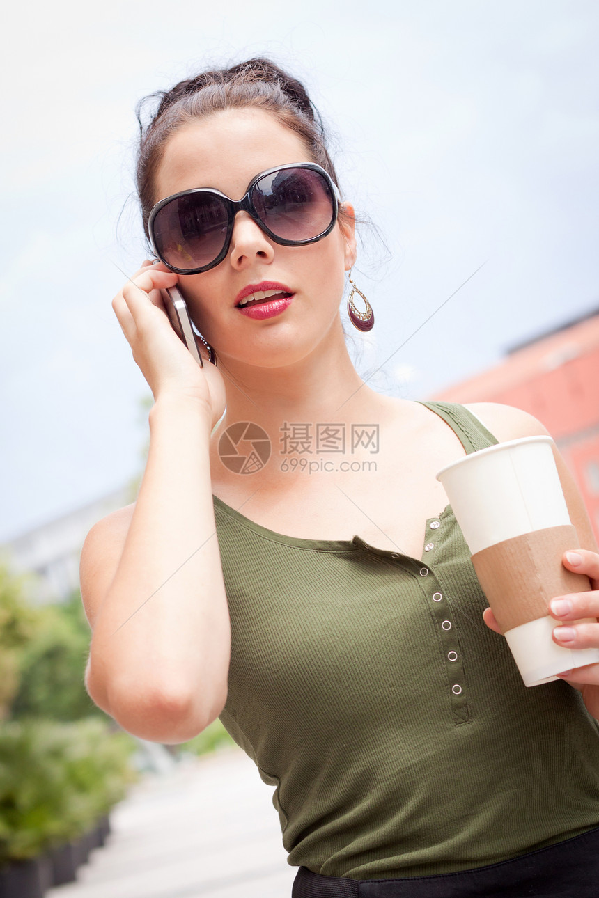 外露有智能手机和太阳镜的漂亮年轻女子杯子饮料拿铁女士咖啡女孩街道女性魅力快乐图片