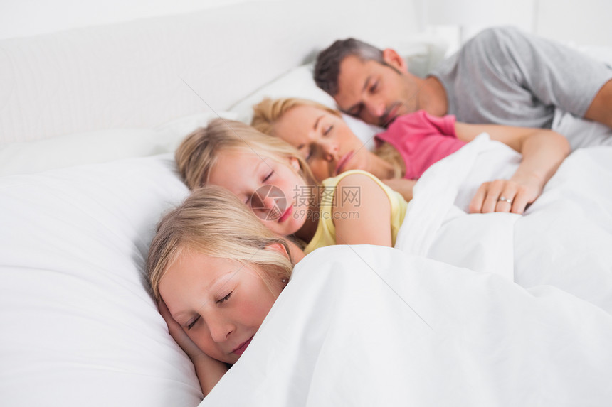 父母与子女一起在床上睡觉;图片
