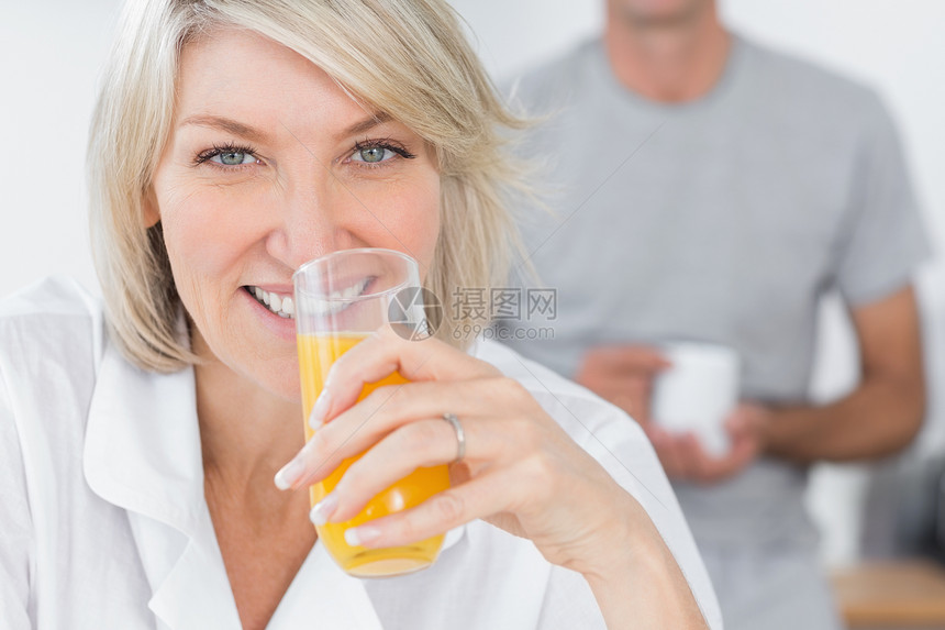 在厨房里喝橙汁的开心女人图片