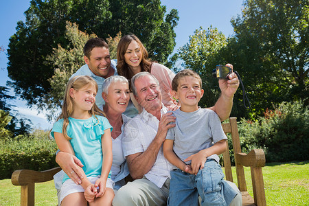 家人坐在长椅上拍照时拍他们自己的照片农村祖父奶奶女孩摄影父亲男生阳光绿地男人背景图片
