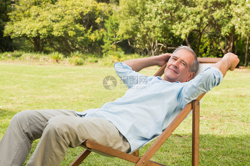 快乐的成熟男人坐在太阳护晒员上图片