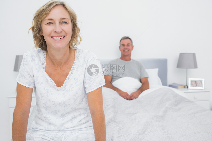 幸福的情侣坐在床对面图片