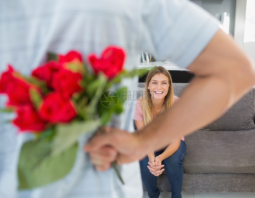 男人在沙发上藏着女友的玫瑰花束图片