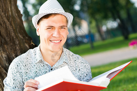 年轻人在读一本书教育学生闲暇班级眼镜青年文学公园幸福男性自然高清图片素材