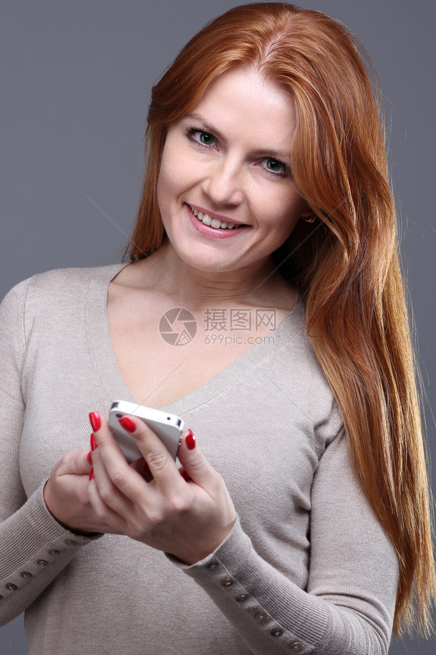 美丽的年轻女子快乐短信女士女性电话手机女孩红发技术享受图片