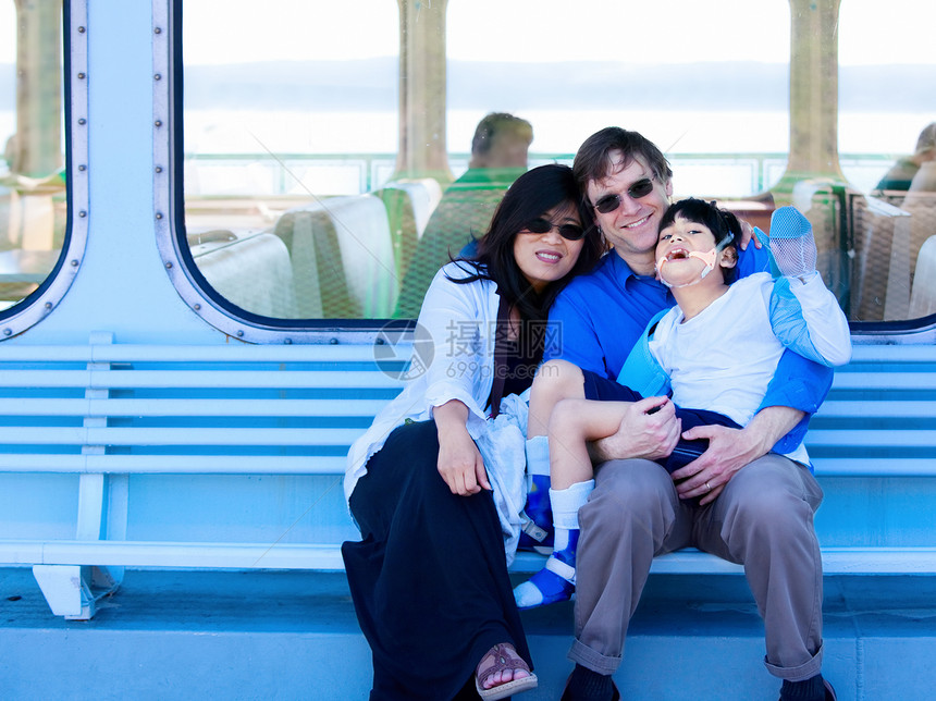 持残疾儿子在渡船甲板上的跨种族夫妇图片