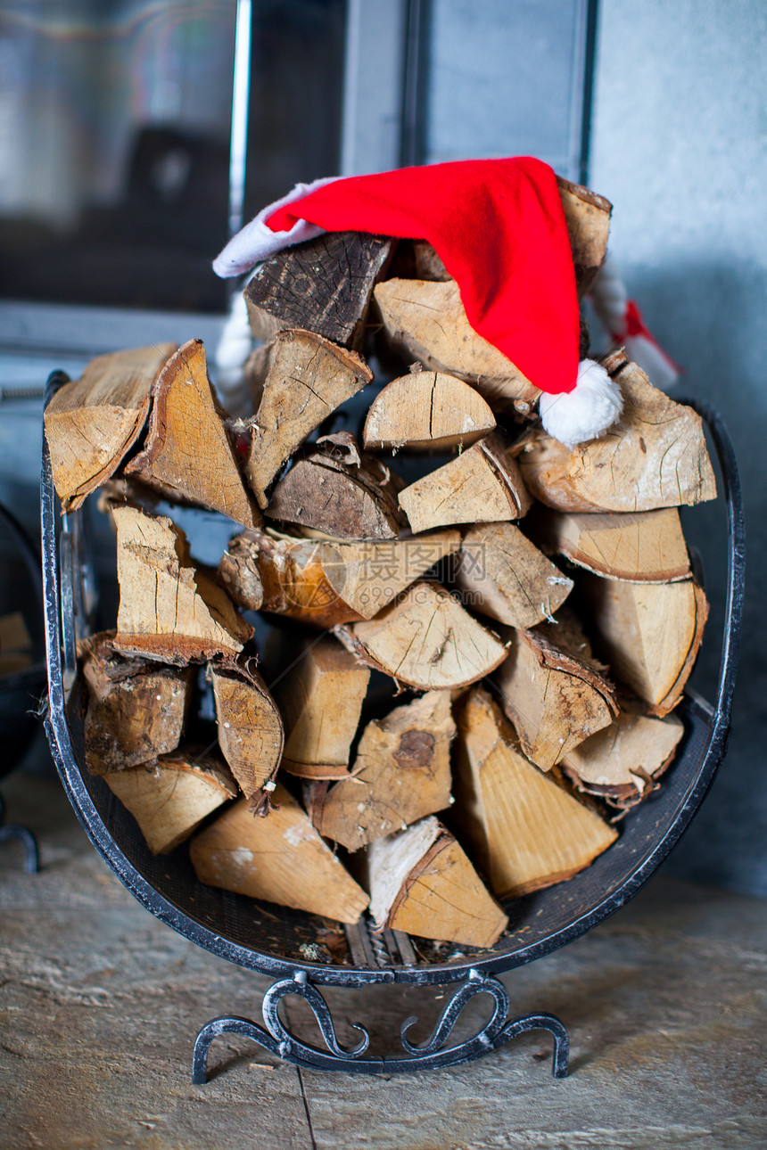 在壁炉附近的房子里戴圣诞老人帽子的木柴乡村木材柴堆木头原木火焰燃料火炉温度大火图片