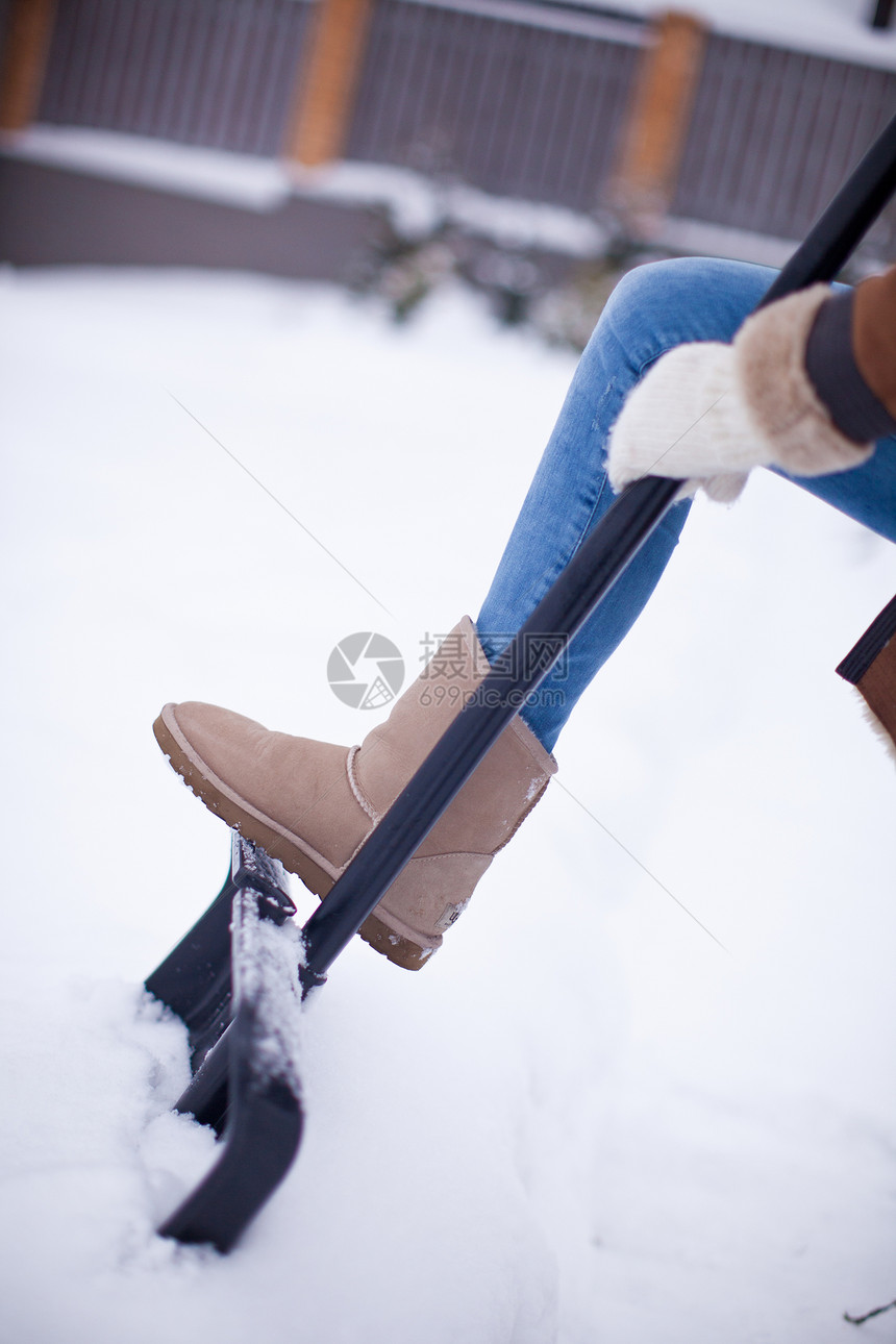 妇女脚在冬季靴子上的雪铁铲上图片