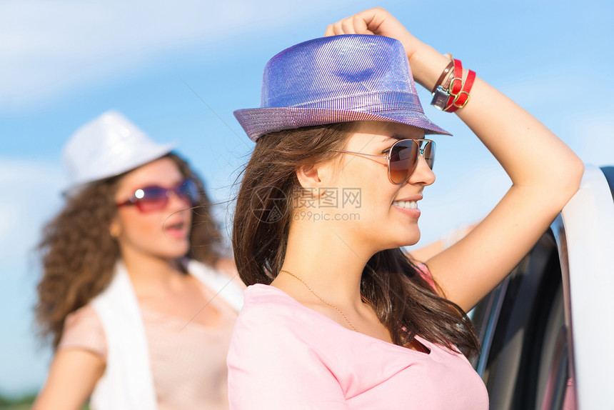 两名身戴墨镜的年轻美女情侣太阳镜假期享受女性微笑日落家庭车辆帽子图片