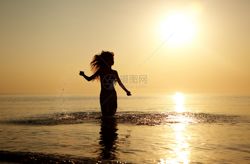 在沙滩上欢乐快乐女性反射头发日落运动动力学海洋跑步海浪阳光图片