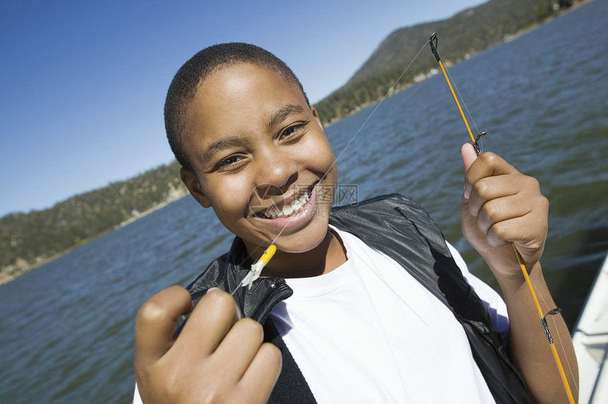 一个快乐的非洲男孩 拿着鱼饵和湖底背景的肖像 他带着渔饵图片