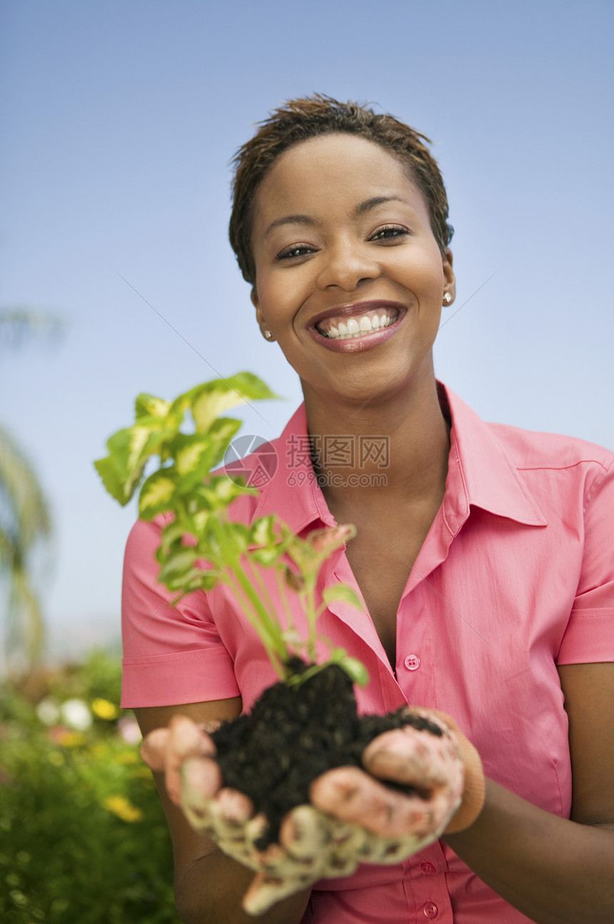 一位快乐的非裔美国女人拿着植物的肖像图片