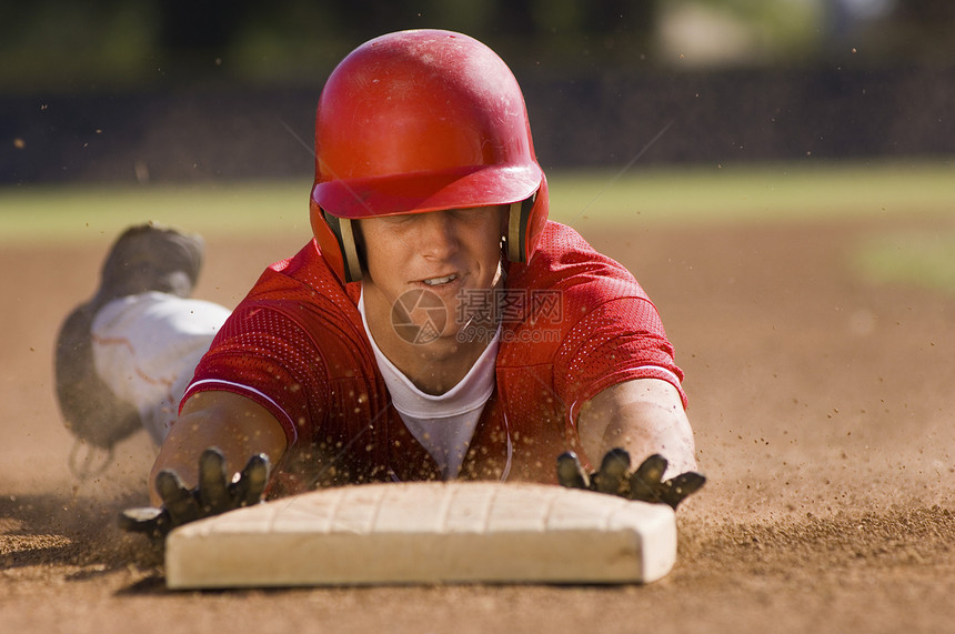 年轻棒球运动员滑向二垒球场的二垒图片