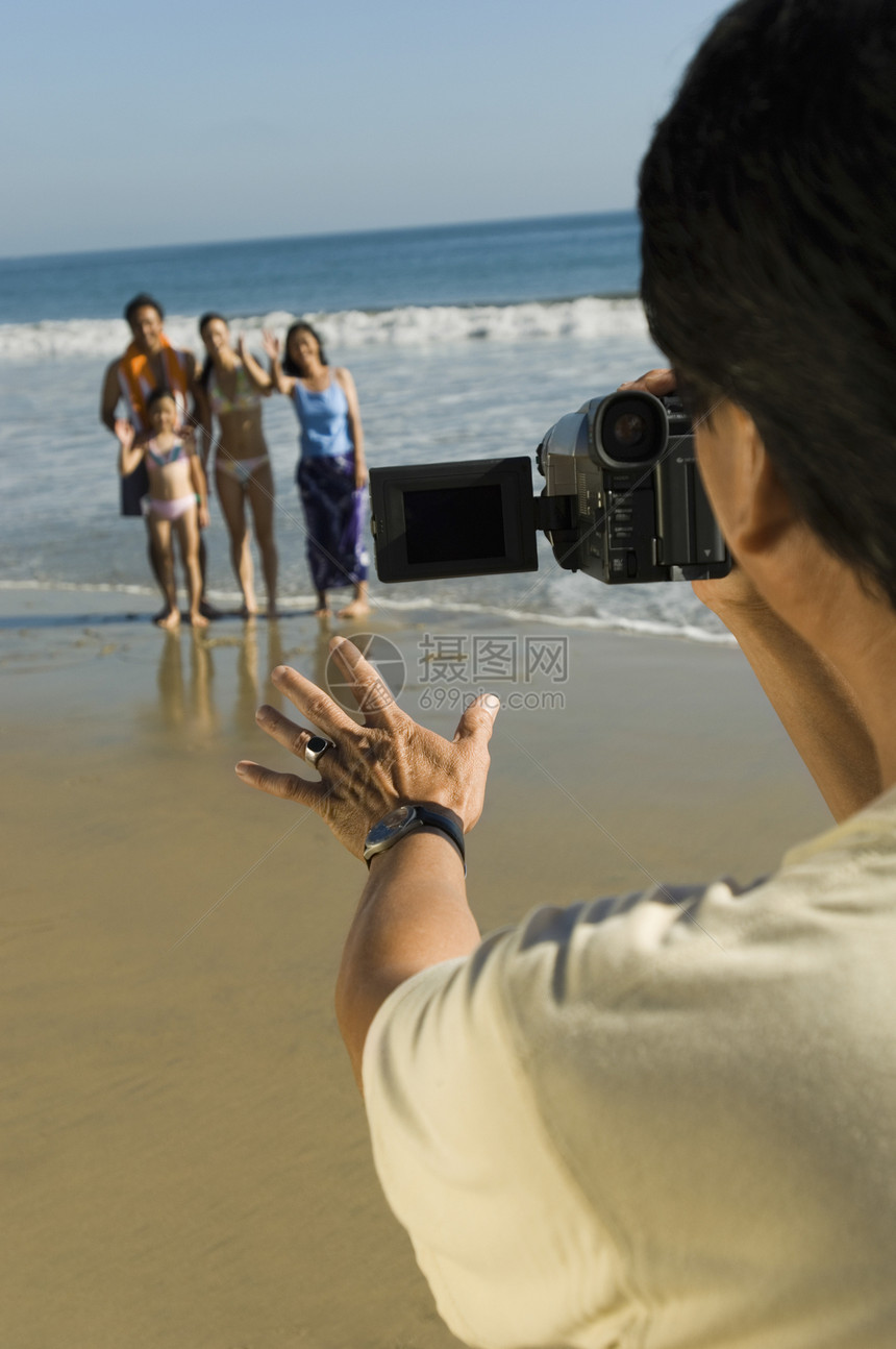 中年男子在海滩上拍摄家庭图片
