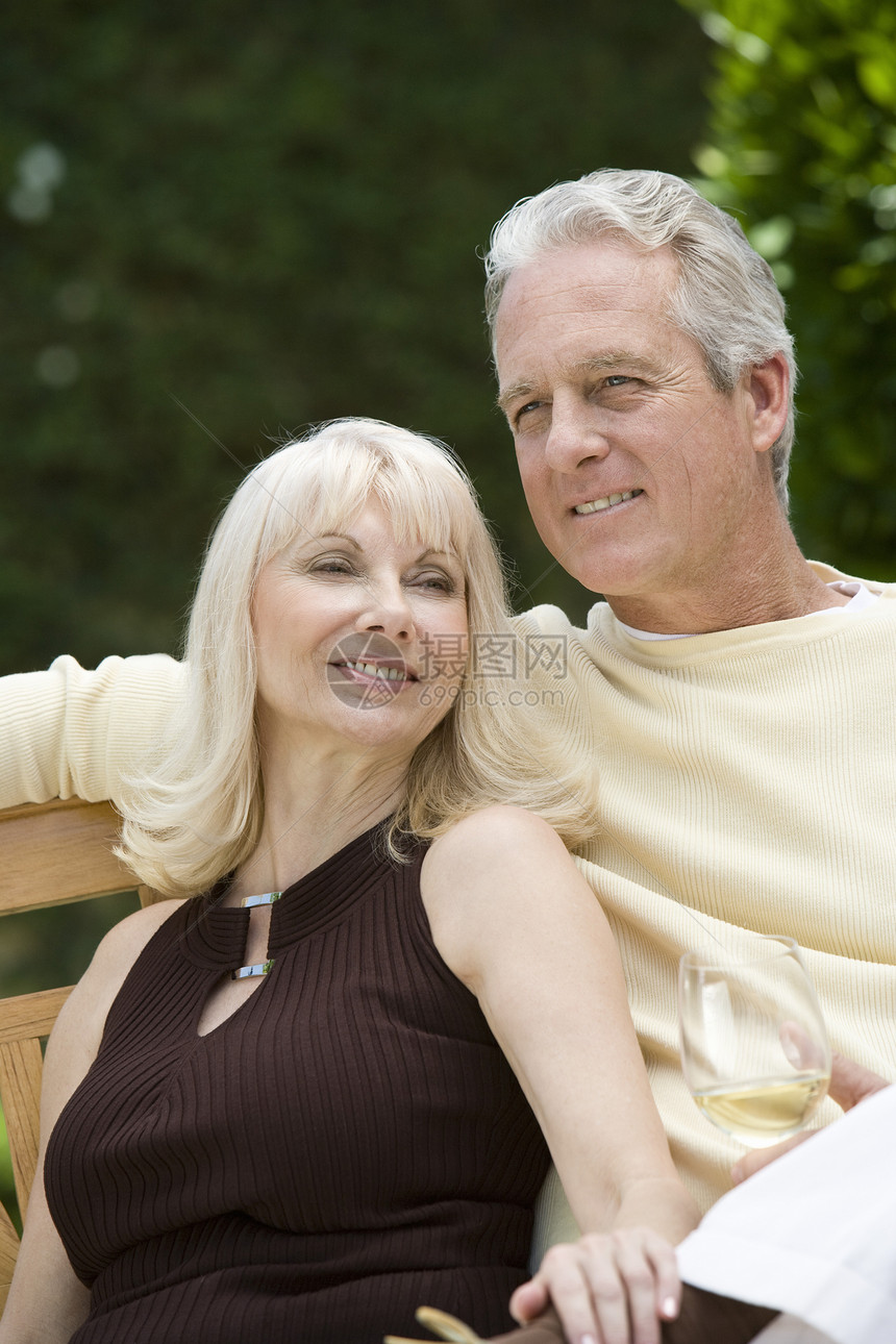 中年夫妇在室外和葡萄酒玻璃板凳上放松图片