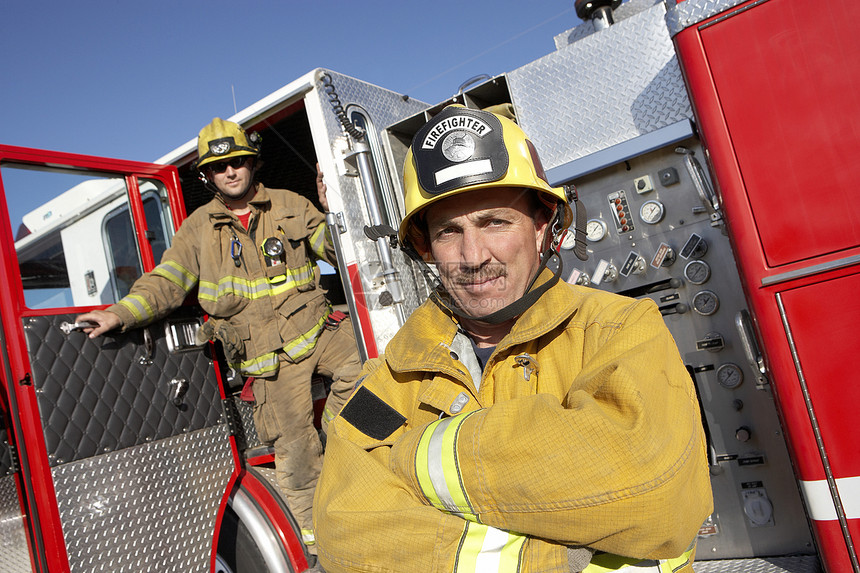 一个充满自信的消防员 和背景中同事的肖像图片