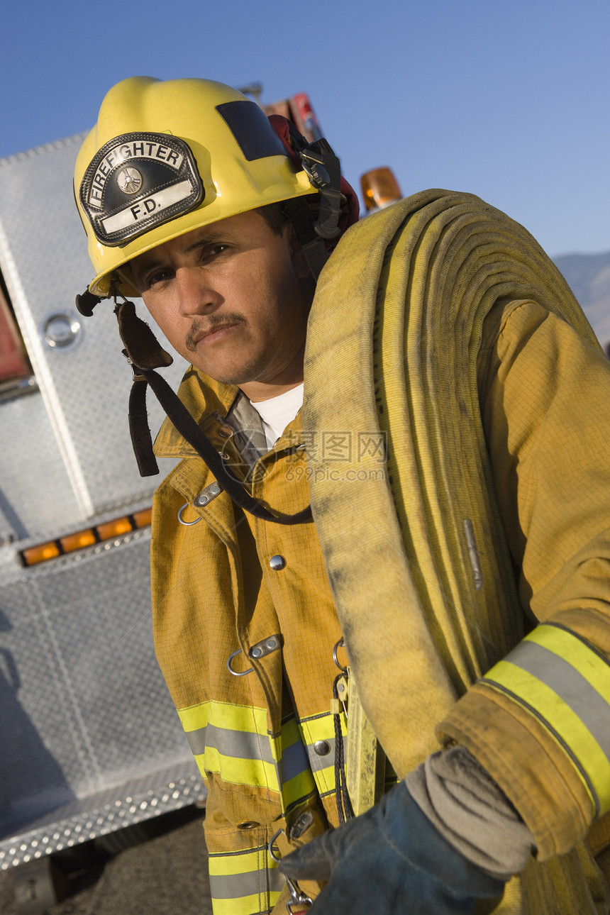 一名肩扛着消防水管的消防战士的肖像图片