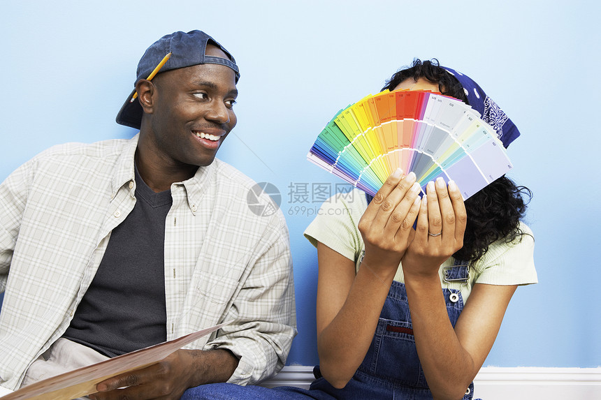 拥有彩色样本的非裔美裔幸福夫妇在新房子上涂漆图片