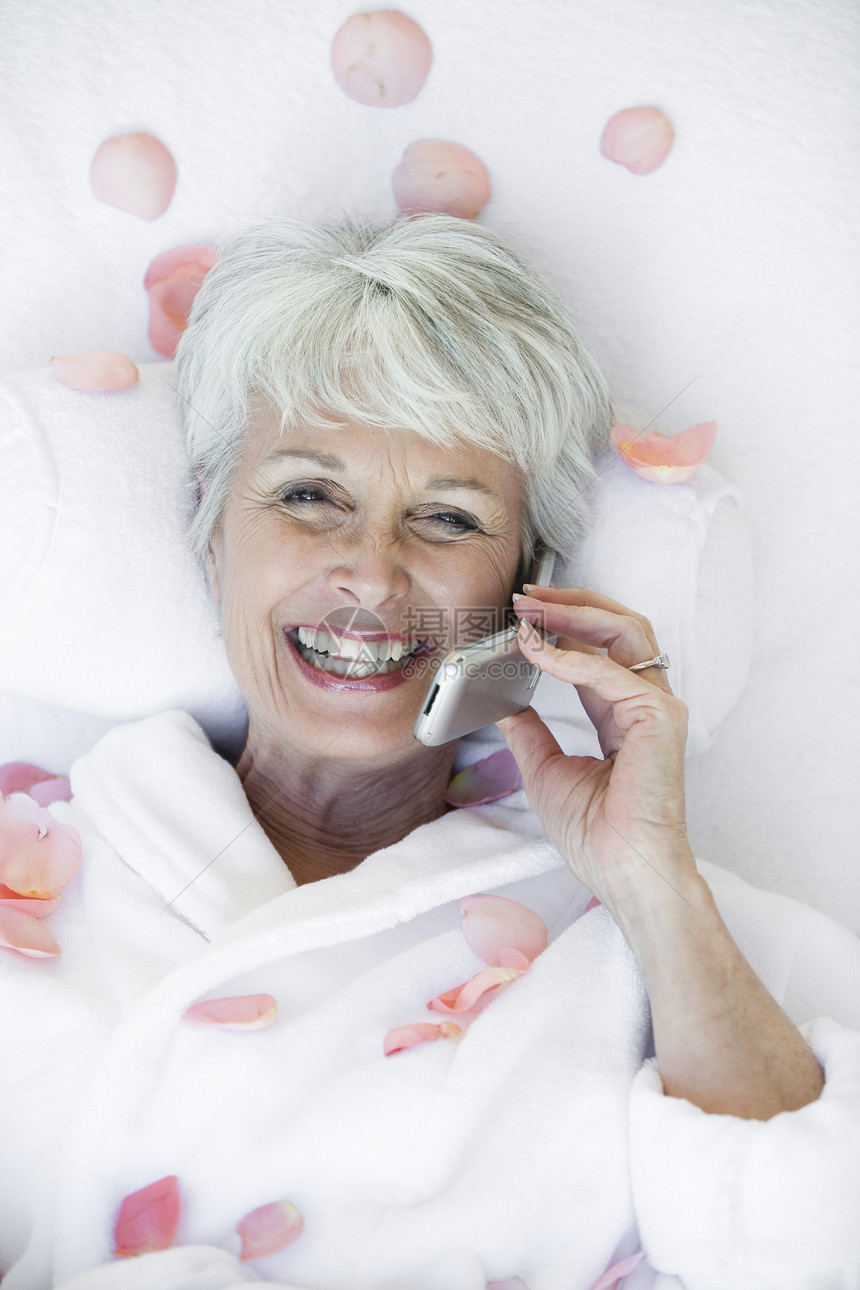 一位躺在按摩床上的老年妇女的高视角和通过手机进行交流图片
