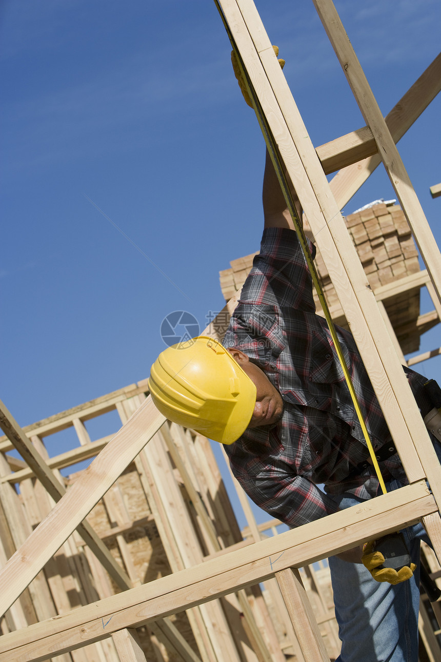在建筑工地测量木束的工人男子服装建筑工人职业安全卷尺结构安全帽倾斜框架图片