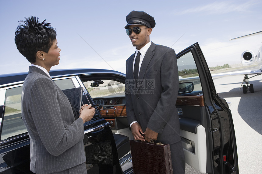 一名非裔美国商业妇女 在机场站着汽车时与司机交流 (b)图片