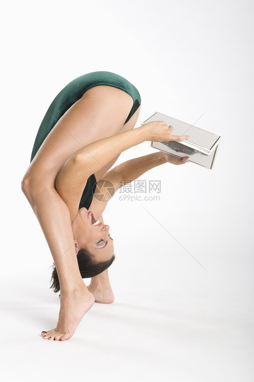 快乐的女子在锻炼时拿着书图片