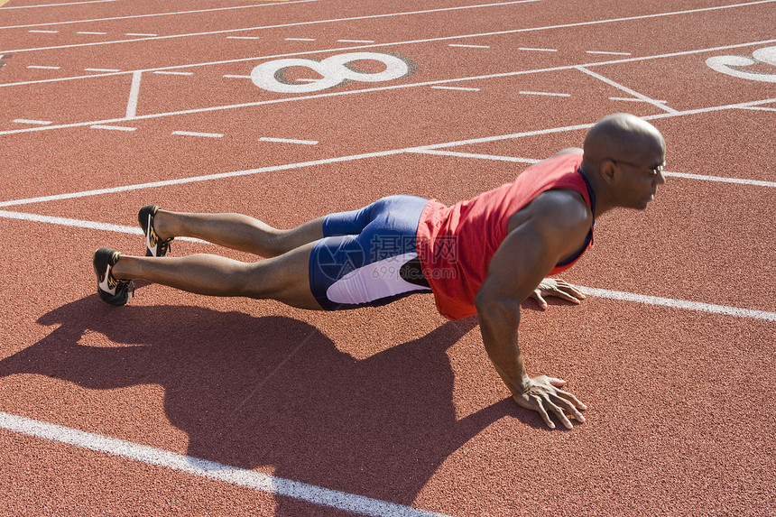 一名非裔美国男性运动员在赛马场上做俯卧撑图片