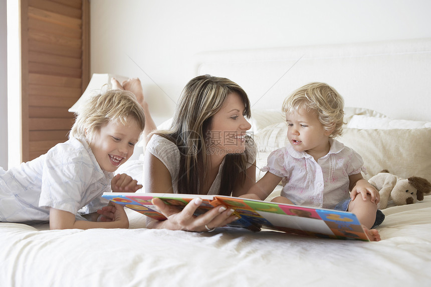 幸福的母亲和儿子在床上读故事书图片