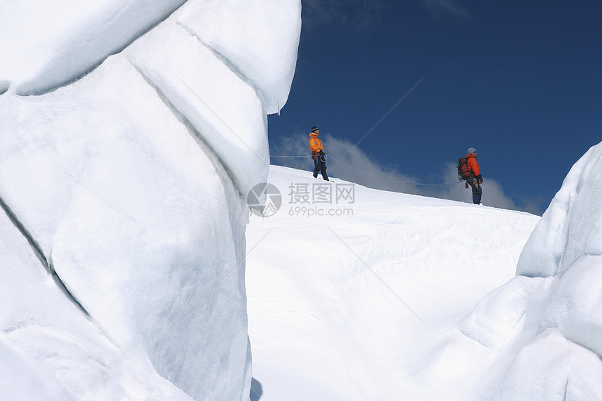 在雪山远处经过冰层的 两位徒步者的侧面景象活动男士假期勘探上坡远足者远足闲暇安全绳索图片