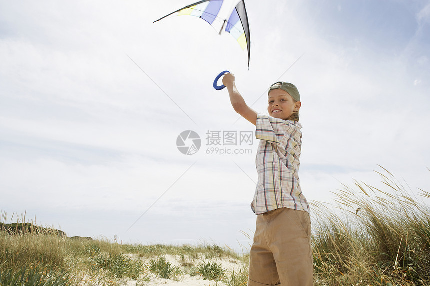 风沙滩上前青少年男孩放风风筝的侧面肖像图片