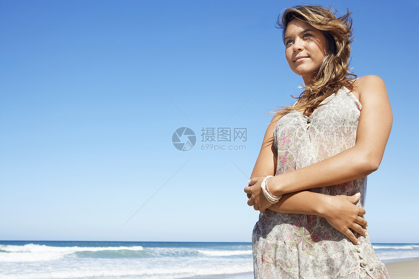 穿着夏装的年轻美女 在沙滩上站立时看远身图片