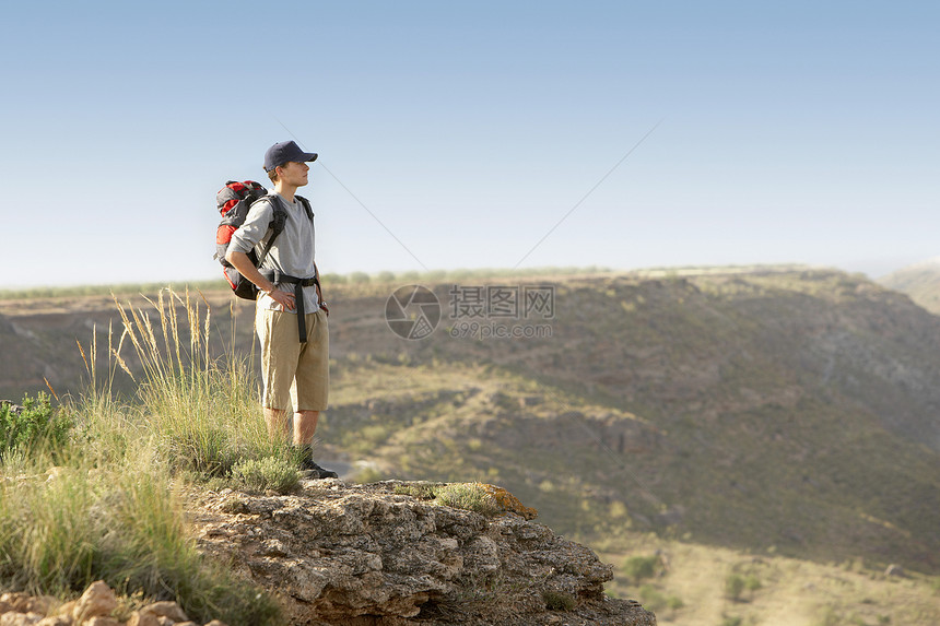 满身的年轻人 背着背包站在山顶上图片