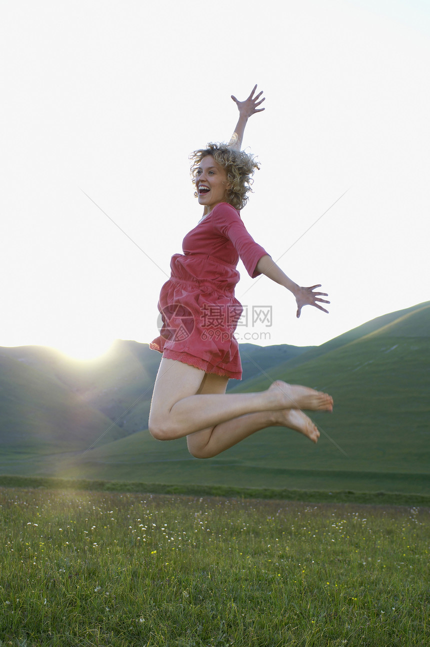 兴奋的年轻女子在公园尖叫时跳跃图片