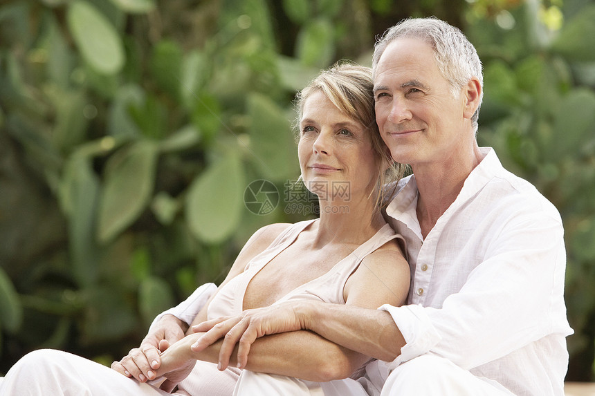 快乐的中年夫妇与双臂在花园放松图片