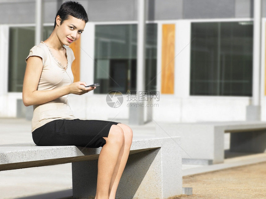 充满自信的年轻女商务人士在广场使用手机的肖像图片