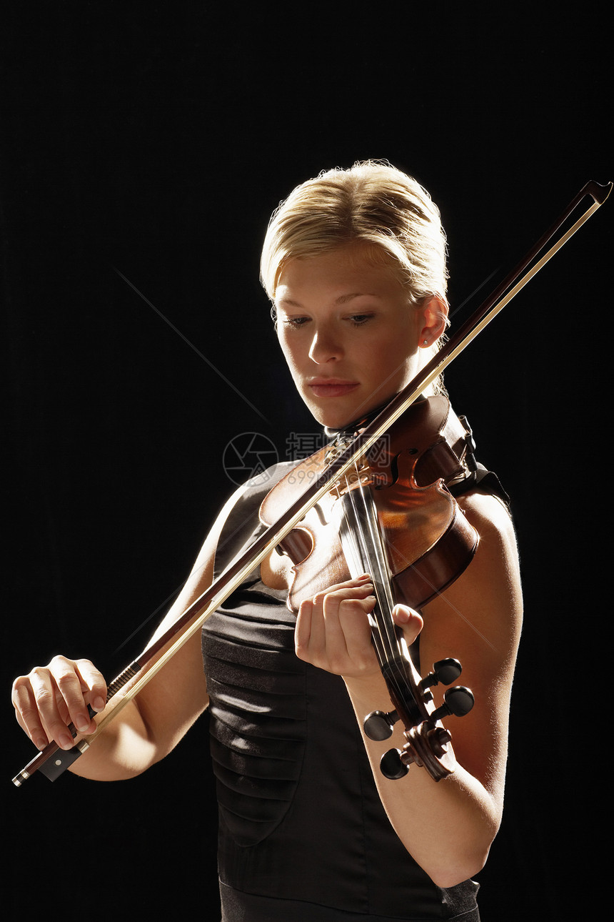 在黑人背景下拉小提琴的年轻女子图片