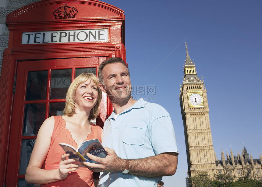 在伦敦电话亭旁站立有导游的两人图片