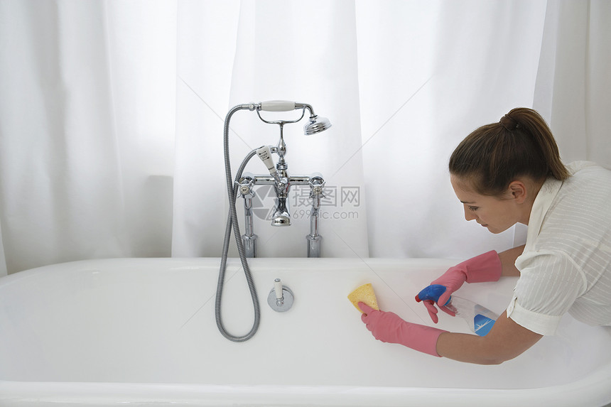年轻女人在家用海绵和清洁工洗浴浴缸图片