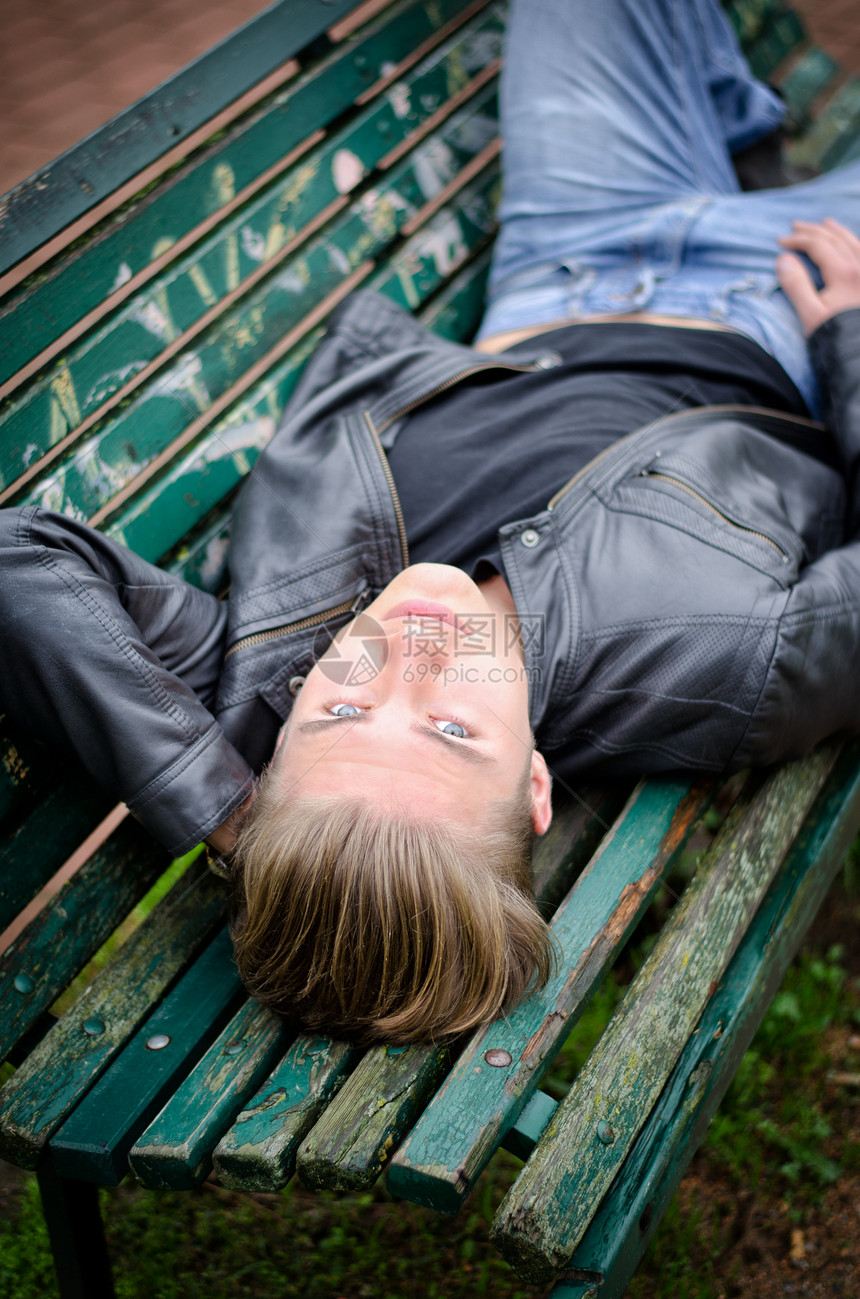 坐在公园长椅上的英俊金发帅美金发年轻男子图片