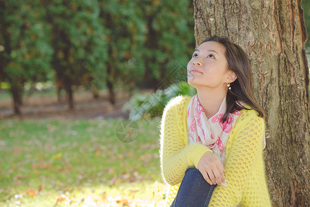 女人坐在树上女孩化妆品叶子花园大学手表季节乐趣眼睛倾斜背景图片