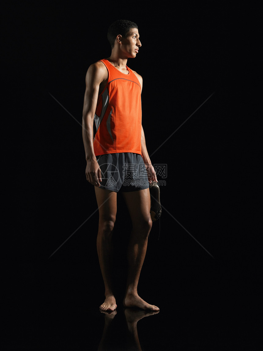 运动员站着拿着鞋的运动员黑人一人成年中年人背景男子田径服装中年专注图片